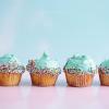 Row of cupcakes decorated with blue frosting and rainbow sprinkles, photo by Brooke Lark